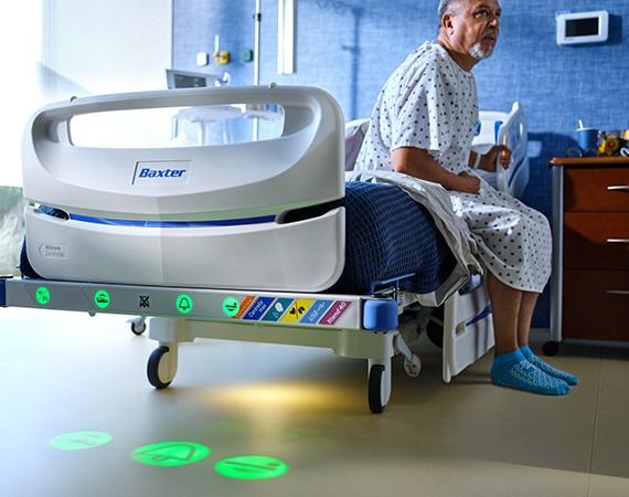 a patient sits in a Centrella hospital bed with SafeView floor projections