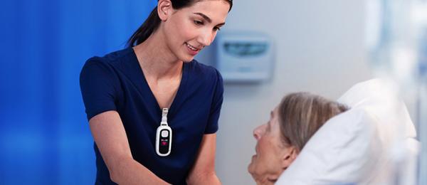 a nurse wears a Voalte Linq device while assisting a patient